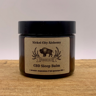 A jar of Nickel City Alchemy CBD Sleep Balm with a label indicating it is a full-spectrum magnesium CBD product