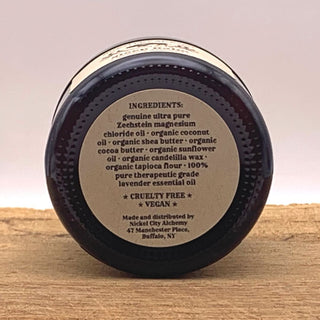 A dark amber glass jar shown from the bottom, displaying Nickel City Alchemy's Magnesium Sleep Balm product ingredients 